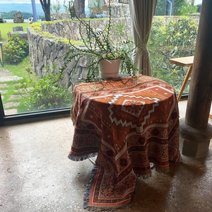 Close-up of bohemian style picnic blanket with orange geometric patterns and woven tassels