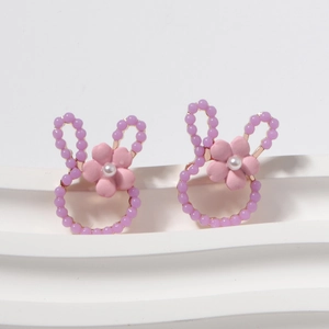 Close-up of rabbit earrings with purple beads, pink flower and white pearl detail
