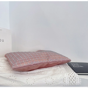 Detail of pink satin bag with silver rhinestone grid pattern on white lace background