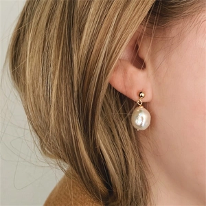 Detailed close-up of a model wearing elegant baroque freshwater pearl drop earrings