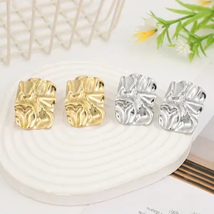 Detailed view of gold and silver irregular liquid lava heart earrings on a stone base