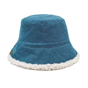 Detail view of blue corduroy bucket hat with white faux shearling trim and small leather patch