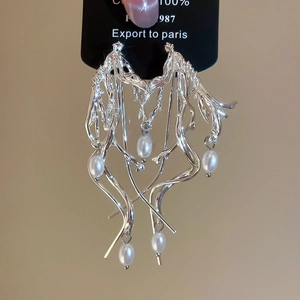 Macro detail of silver needle branch earrings featuring elegant white teardrop pearls