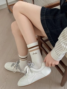 Close-up of white athletic crew socks with stripes and Smile embroidery on wood