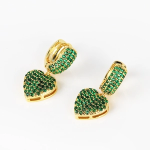 Detail of gold-plated heart earrings with green pave-set stones on a white background