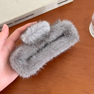 Gros plan d'une grande pince à cheveux grise en fausse fourrure à texture pelucheuse