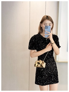 Mirror selfie showing a golden geometric acrylic clutch bag paired with a sequined black dress