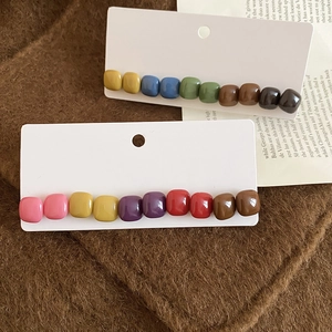 Detailed view of colorful square resin bead hairpins on minimalist background