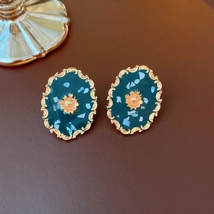 Macro detail of vintage oval earrings with green resin and gold sunburst accents