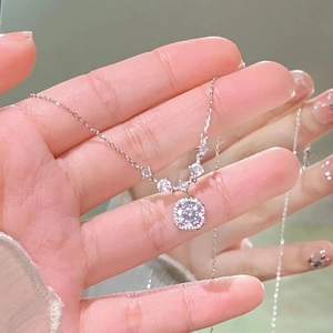 Detailed view of silver necklace with square halo pendant and diamond-studded chain