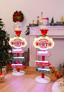 Close-up of lighted Christmas North Pole sign with glowing snow globe and LED arrows