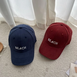 Detail of embroidered BEACH logo on navy and wine red cotton twill baseball caps