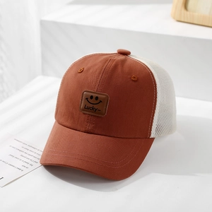 Detail view of a brown mesh truck cap with a square smiley face leather patch and Lucky text