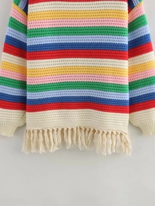 Détail d'un pull en tricot à rayures arc-en-ciel avec des franges élégantes sur l'ourlet