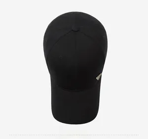 Close-up of the black baseball cap showing cotton twill texture and gold metal logo