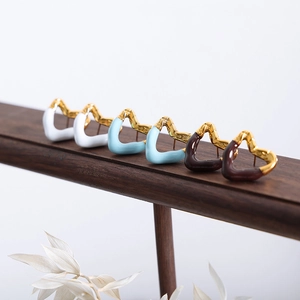 Three pairs of vintage gold heart earrings in white, blue and coffee enamel on wood stand