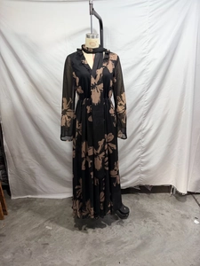 Detail of elegant black chiffon maxi dress with beige floral print and matching scarf neck