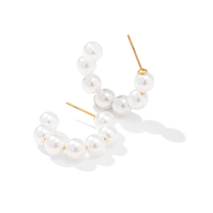 Detail view of large white pearls on C-shaped gold-plated stainless steel hoop earrings