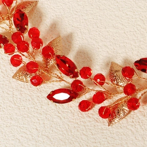 Detailed close-up of handmade bridal headband with gold leaves and red crystal accents