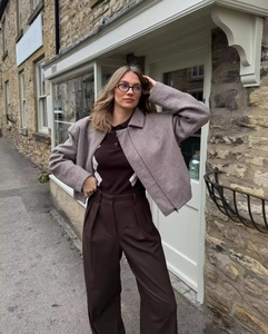 Photo en extérieur d'une veste en tweed marron à fermeture éclair et d'un pantalon large