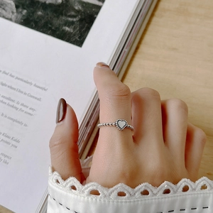 Close-up of a 925 sterling silver beaded ring featuring a white heart charm on a hand