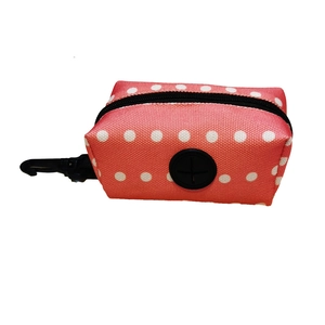 Close-up of orange polka dot pet waste bag holder with black clip and rubber dispenser