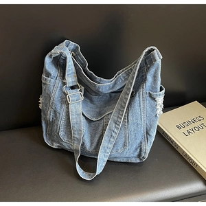 Détail du sac fourre-tout en denim bleu avec texture délavée et bords effilochés