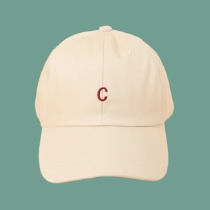 Close-up of red embroidered C letter on beige cotton twill baseball cap fabric