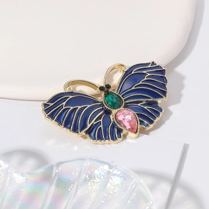 Broche papillon vintage en émail bleu avec cristaux colorés sur un support de luxe