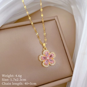 Close-up of gold flower necklace with pink gem and zircons on beige jewelry box