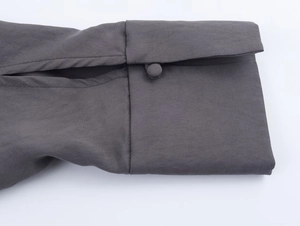 Detailed close-up of charcoal grey blouse cuff with fabric-covered buttons and fine stitching