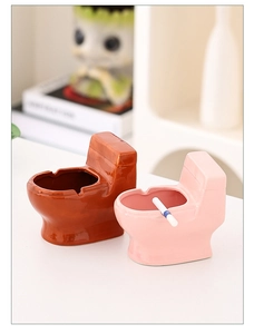 Detailed view of pink and brown toilet-shaped ceramic ashtrays on a desk