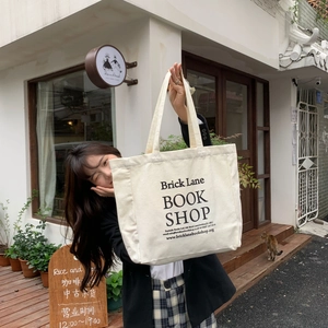 Detailed view of white canvas tote bag with black Brick Lane Bookshop print on street