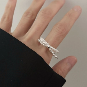 Detailed view of a silver bow knot ring made of white pearls worn on a female finger