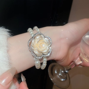 Detail of elegant double-layered pearl bracelet featuring a crystal-studded resin flower