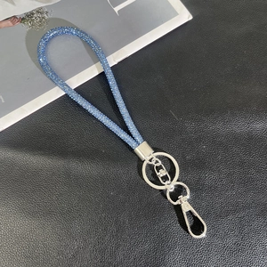 Detail of royal blue rhinestone phone lanyard with silver metal clasp on black background