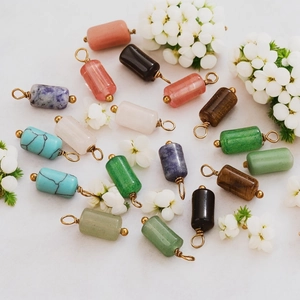 Detailed flat lay of cylindrical natural stone pendants with gold-plated caps and loops