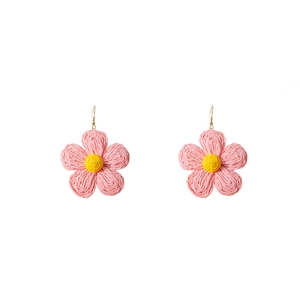 Detail of handmade woven raffia flower earrings with pink petals and yellow stamens