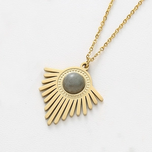 Détail macro d'un pendentif rayon de soleil doré serti d'une pierre naturelle grise