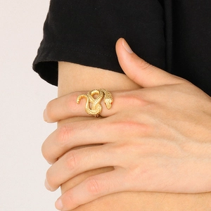 Dettaglio ravvicinato di un anello a forma di serpente dorato con occhi rossi al dito