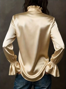 Detail of elegant champagne satin shirt showing ruffled collar and back drape texture