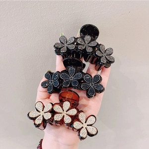 Dettaglio di tre eleganti mollette per capelli con fiori di strass neri, blu e dorati