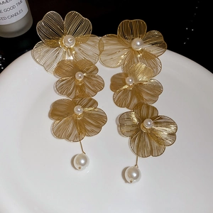 Dettaglio degli orecchini a fiori intrecciati dorati a tre strati con perle