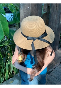 Detail of the natural straw texture and black satin bow on this wide brim sun hat