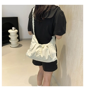 Detail of a beige pleated nylon tote bag featuring a drawstring closure and twisted strap