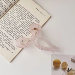 Pink jelly bow hair claw clip placed on a book for a gentle aesthetic look