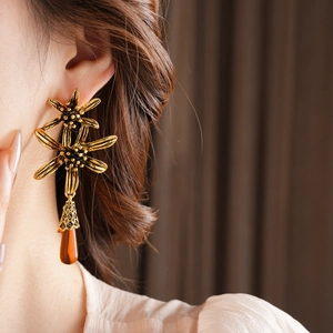 Close-up of vintage gold flower earrings with amber water drop tassels on a female model