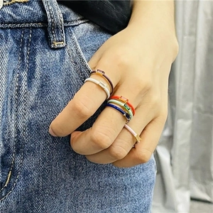 Close-up of colorful enamel 18k gold rings with rectangle zircon layered on fingers