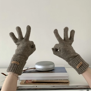 Detail of grey-brown knit gloves with ribbed cuffs and Hand Made leather label
