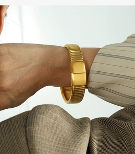Detail of golden Tubogas wide cuff bracelet featuring a sleek rectangular clasp buckle